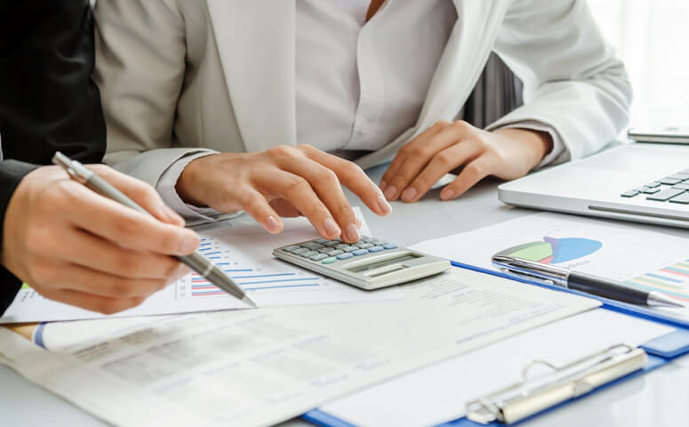 Two accountants checking figures on calculator